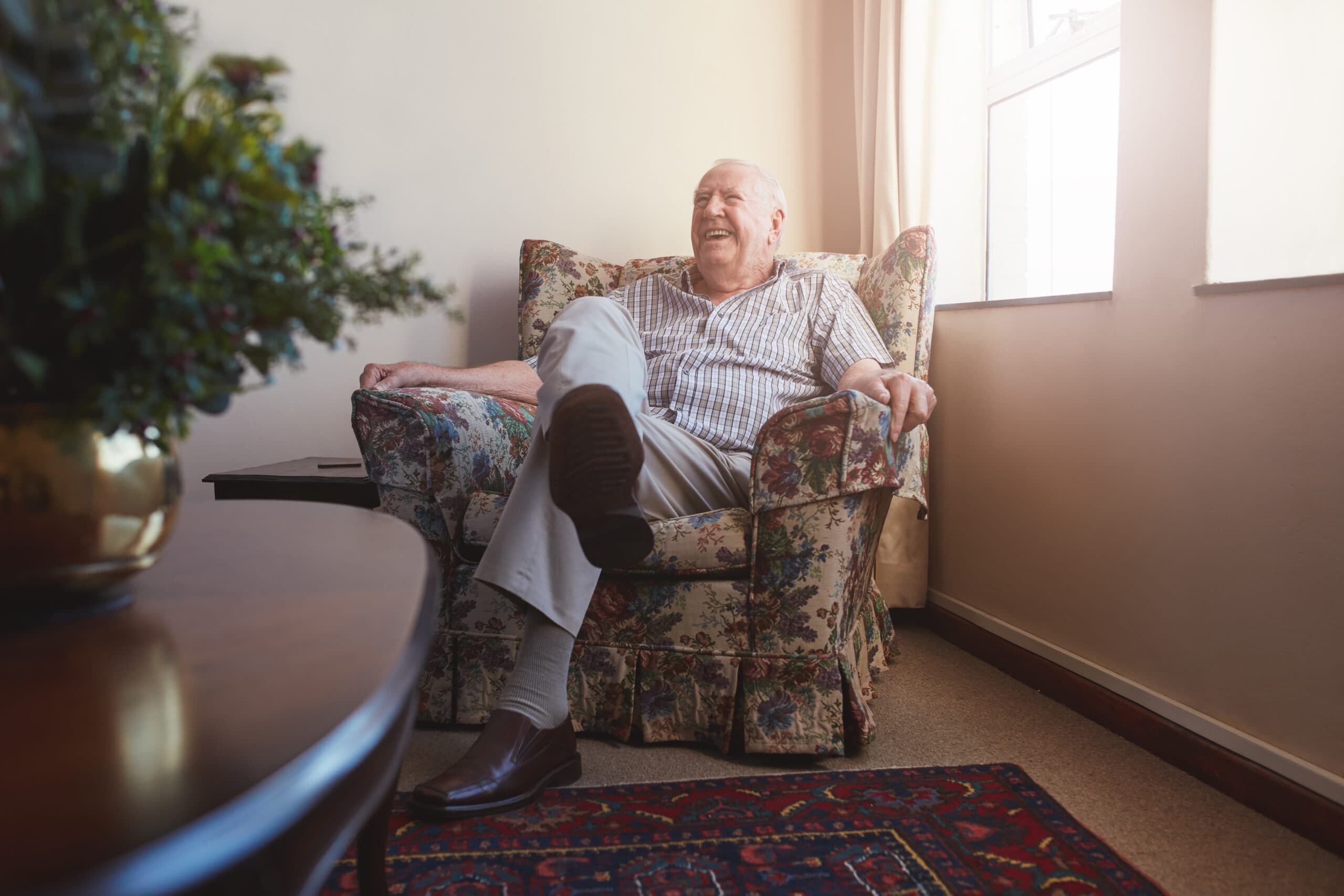 Elderly man sitting on arm chair at old age home Benefits Of Care Jobs