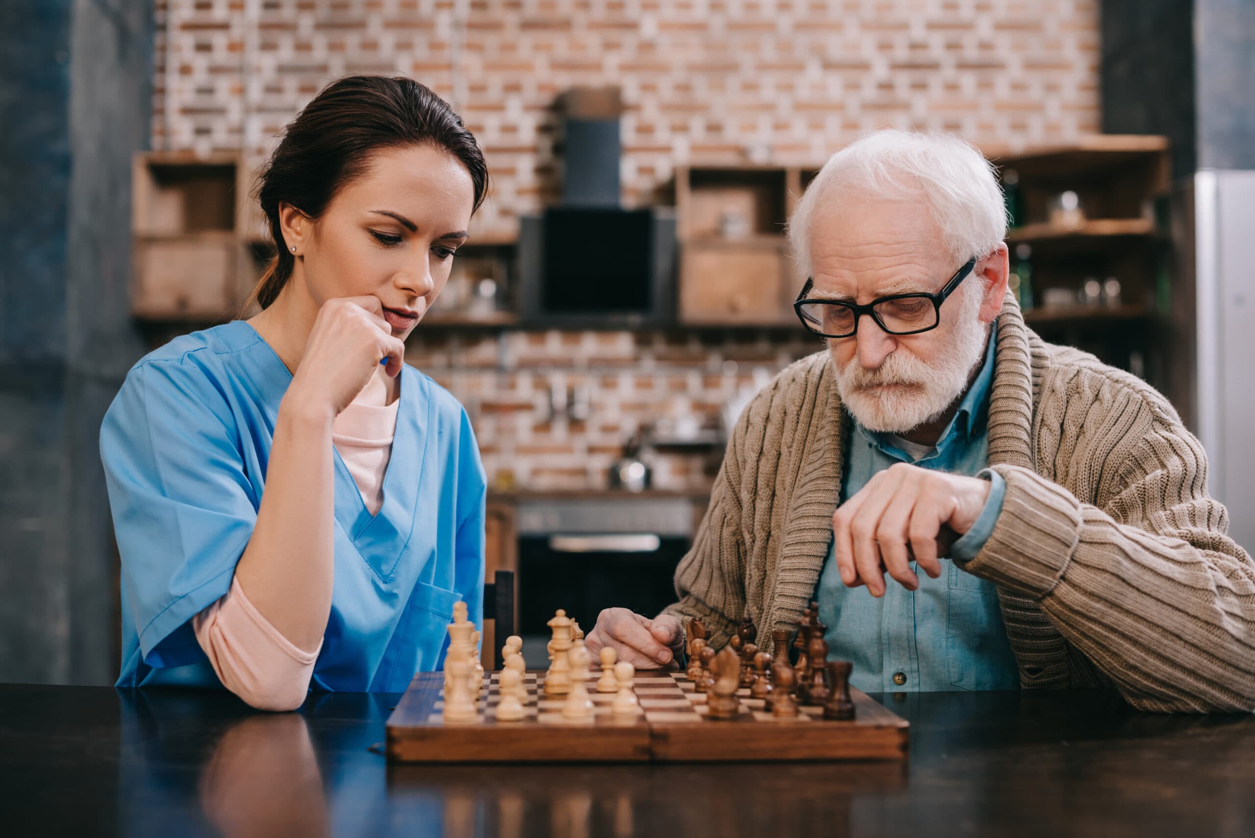 Old man and female caregiver playing chess Old man and female caregiver playing chess