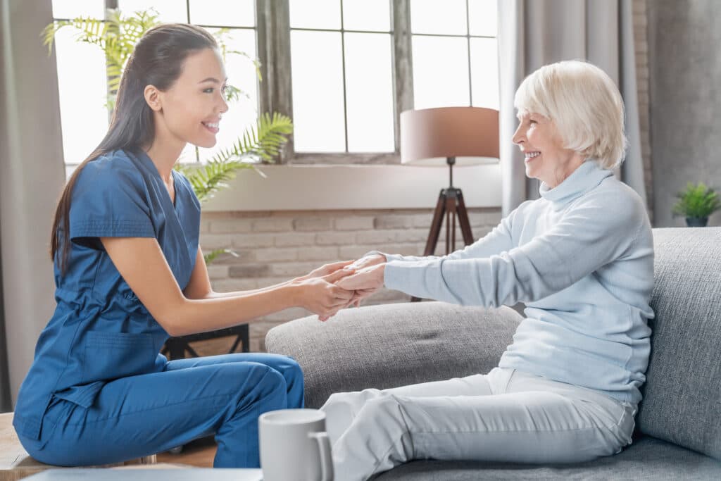 Assisting senior people. Female caregiver holding elderly woman's hands indoors Homecare Support