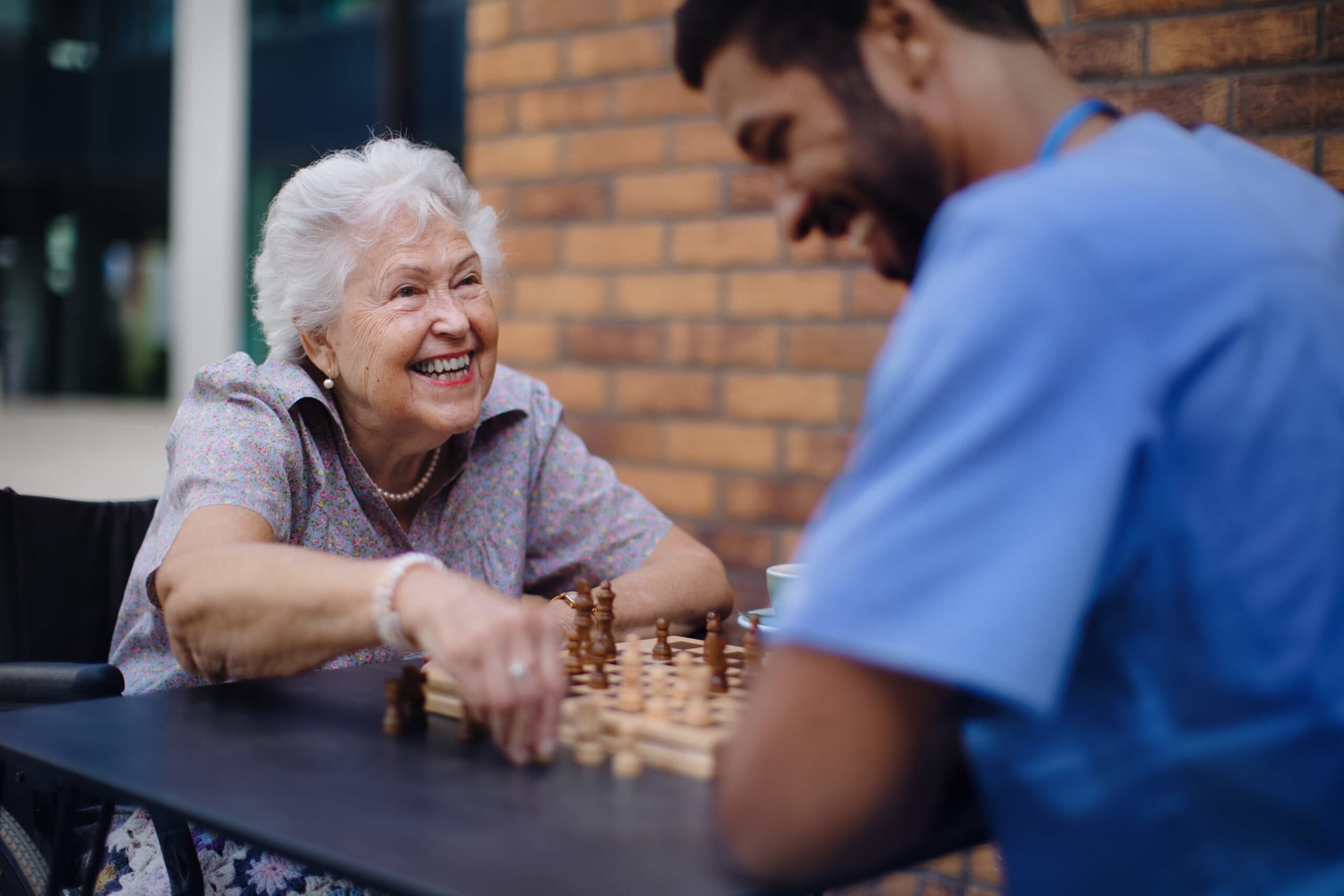 Caregiver playing chess and drinking coffe with his client outdoor at cafe. The Benefits of Having Hobbies in Later Life